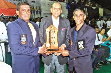 Chief Guest Gamini Marapona who captained S. Thomas’ College in 1960 handing over the Orville Abeynaike Memorial Trophy to the two captains Sajana de Zoysa (Royal on left) and Javindi Peiris of S Thomas’ at the   conclusion of the 17th Battle of the Blues hockey encounter at the Astro   turf yesterday. (Pictures by HERBERT PERERA)
