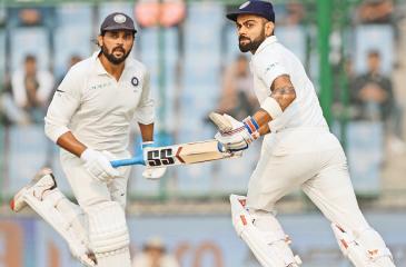 Indian captain Virat Kohli and opening bat Murali Vijay who hit a century apiece and figured in a ---century stand partnership for the third wicket running between the wickets on the first day of the third and final cricket Test against Sri Lanka at the Feroz Shah Kotla Stadium in Delhi on Saturday.  AFP