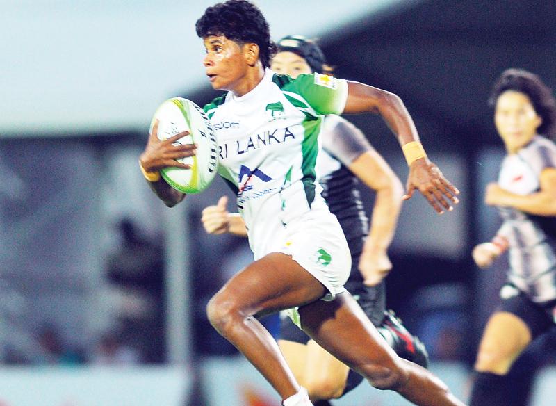Sri Lanka women’s winger Dulani Palikondage on her way to scoring one of her two tries against Singapore in a group match played at the Racecourse international stadium yesterday.    