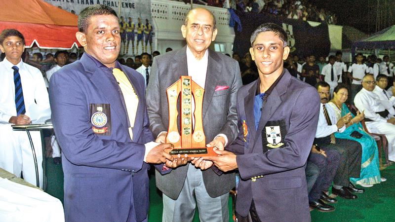 Chief Guest Gamini Marapona who captained S. Thomas’ College in 1960 handing over the Orville Abeynaike Memorial Trophy to the two captains Sajana de Zoysa (Royal on left) and Javindi Peiris of S Thomas’ at the conclusion of the 17th Battle of the Blues hockey encounter at the Astro turf yesterday. (Pictures by HERBERT PERERA)