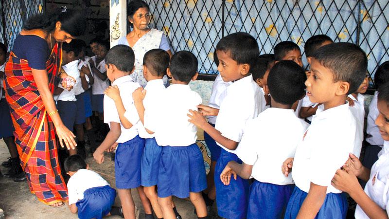 Schoolchildren pay obeisance to their class teacher on World Teacher’s Day.	 Pic: Sulochana Gamage