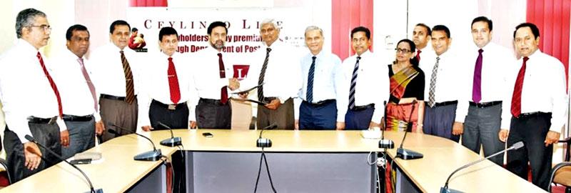 Ceylinco Life, Managing Director R. Renganathan (centre right) and Post Master General Rohana Abeyaratne exchange the agreement between the two entities.