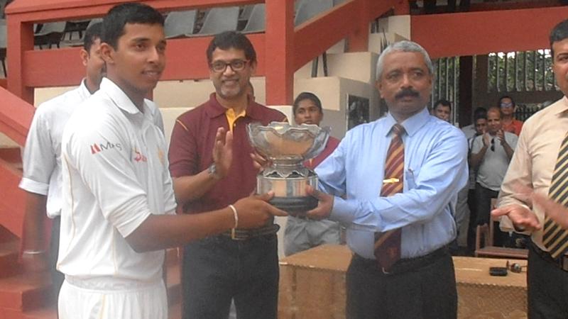 Ananda College principal S.M. Keerthiratne returns the L.D.H. Peiris memorial trophy to Royal captain Helitha Vithanage.    