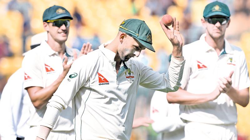 Australian spinner Nathan Lyon shows the ball with which he scalped eight Indian batsmen as he is cheered by team mates at the end of the innings on the first day of the second Test at Bangalore on Saturday. AFP    