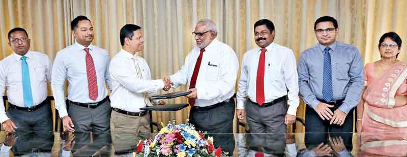 Commercial Bank Managing Director/CEO Jegan Durairatnam (fourth from right) exchanges the agreement with Tilak Dias Gunasekara, Managing Director of Sathosa Motors. Senior executives of the two institutions look on.     