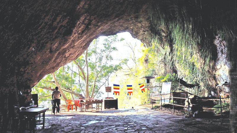 The arched cave mouth of Batatotalena with ferns hanging on the rock ceiling constantly dripping water. 