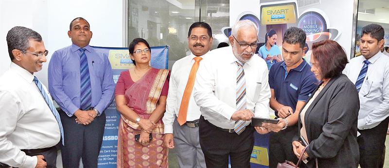 Commercial Bank Managing Director Jegan Durairatnam (fourth from left) enrols a customer through the tab based app at the Wellawatte branch. Members of the senior management of the Bank look on.     