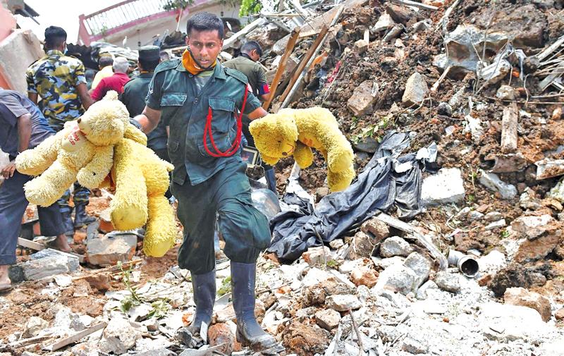 Sri Lankan Army soldiers walk past damaged houses after the collapse of a garbage dump in Meetotamulla, on the outskirts of Colombo on April 17, 2017. AFP