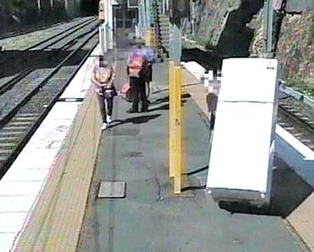 A man wheels a refrigerator across the platform at an Australian train station before boarding a commuter train. Screenshot: Queensland Rail/Facebook   