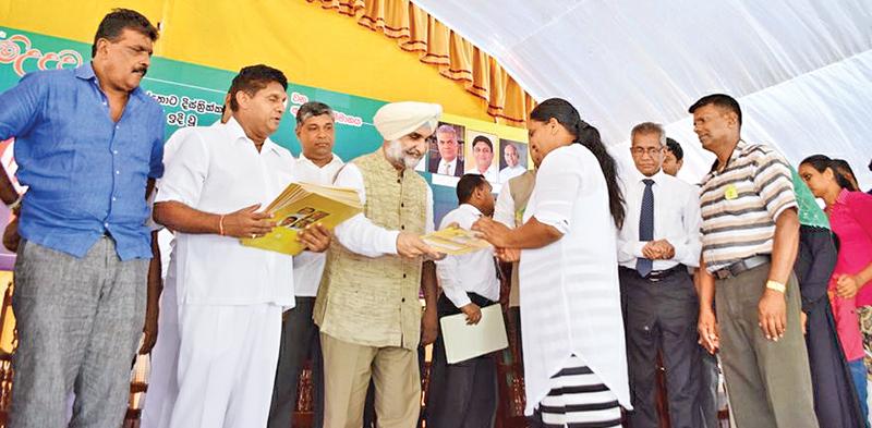Indian High Commissioner Taranjit Singh Sandhu hands over the title deed to a beneficiary. Housing Minister Sajith Premadasa looks on.