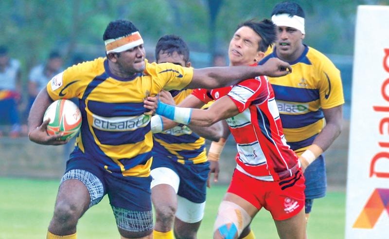 Army Sports Club's Number Eight Manoj Silva warding off a tackle from CH and FC's Avishka Lee in their Diolog ‘A’ division league Rugby match played at the Race Course yesterday which Army SC won 20-15 Picture by Hirantha Gunathilake