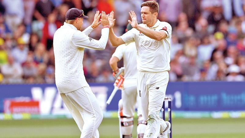 England bowler Chris Woakes (R) celebrates with captain Joe Root (L) after dismissing Australian batsman David Warner.- AFP 