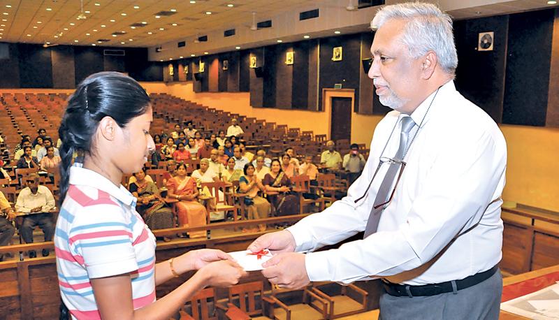 An undergraduate receives the scholarship from Prof. Lashman Dissanayake.