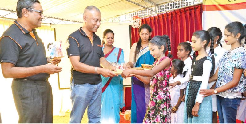 Director of Crysbro Shafeek Samad handing over stationery items to a student