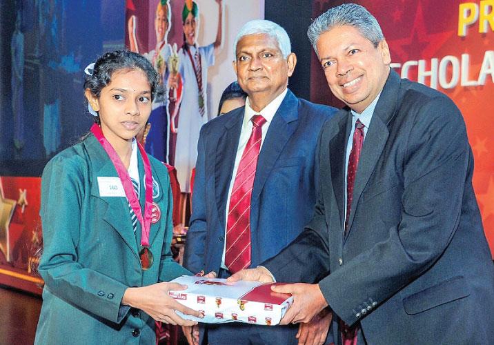 A Pranama recipient receives a National Merit Award from chief guest Prof. Ajantha Dharmasiri. Ceylinco Life  Managing Director R. Renganathan looks on.    
