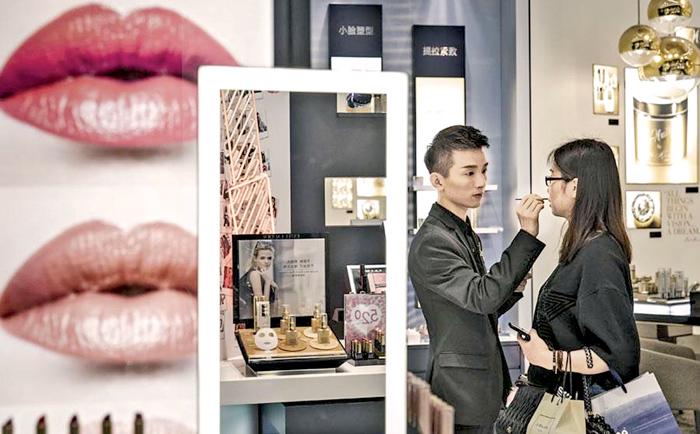 A sales assistant helps a customer try out cosmetic products at a department store in Shanghai  