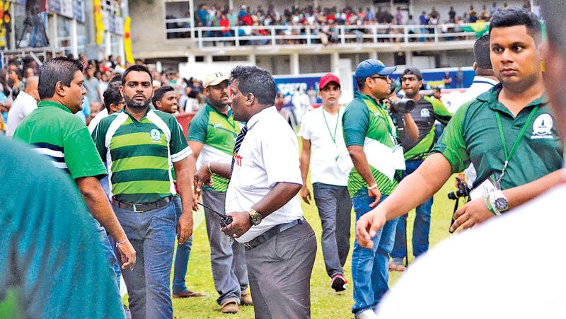 Old boys of Isipathana College attempt to control a boisterous set of supporters who hurled  objects onto the field