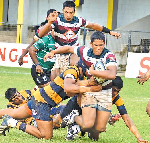 Zahira College player Shamin Nassar pushes through the grip of a tackle in his team’s inter-school second round League rugby match against Royal College at the Royal Complex ground in Colombo yesterday. (Picture by Saman Mendis)    