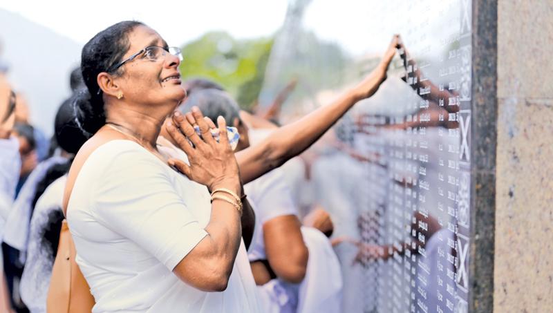 Tribute to Fallen Heroes: Overcome with emotion and memories, a mother of a fallen hero looks up her son’s name among the names inscribed at the Memorial. (Pic: Chinthaka Kumarasinghe)