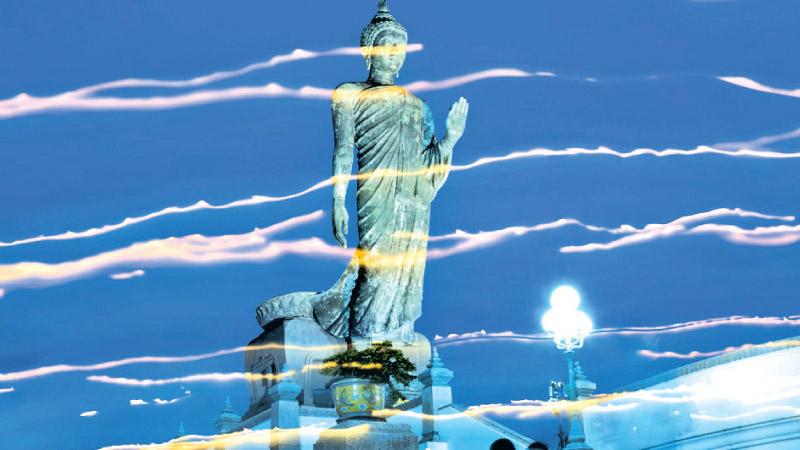 Streaks of light from candles mark the paths of the followers of Buddhism as they walk around the giant statue of Lord Buddha at the Phutthamonthon in Nakhon Pathom