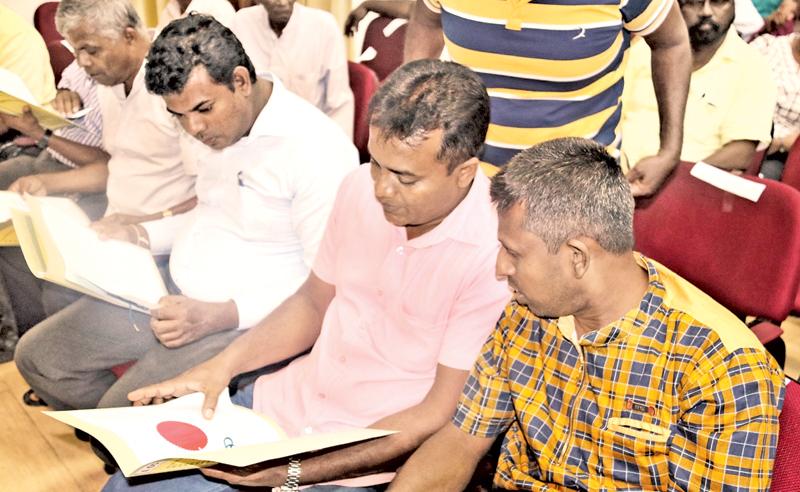 Recipients of title deeds browse through the documents.