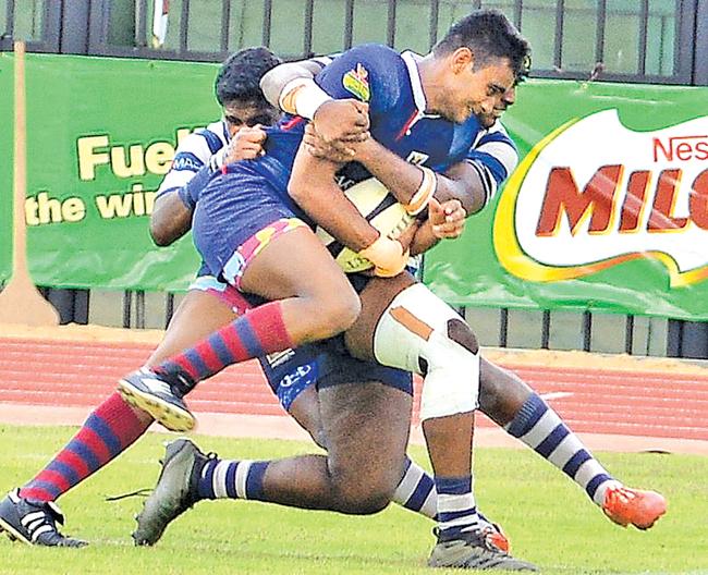 Kingswood College player Weligampola is held by two defenders from St. Joseph’s College in their Milo trophy semi final rugby match at the Sugathadasa stadium in Colombo yesterday. Pic: Saman Mendis