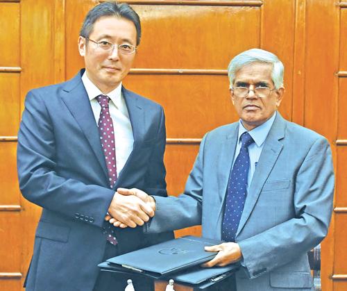 Secretary, Ministry of Finance and Mass Media, Dr. R.H.S. Samaratunga and Chief Representative of JICA Sri Lanka office Fusato Tanaka exchange copies of the agreement. 
