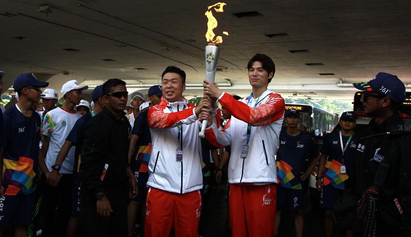 Chinese runners handover the torch during the last torch relay in Jakarta on August 18, 2018, ahead of the opening ceremony of the 2018 Asian Games. (AFP)