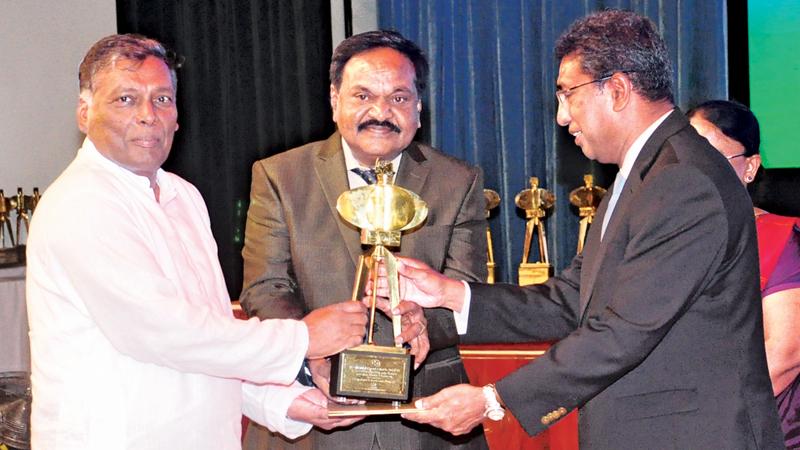 Chairman / Managing Director, Narayanasamy Gokulakrishnan receives the award from Minister Harsha de Silva. Director Sinnathamby Balasundaram looks on.   