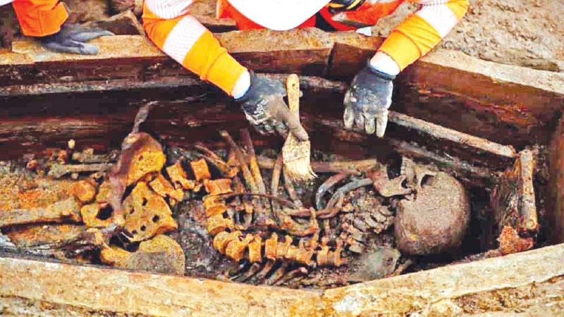 A field archaelogist uses a brush on a skeleton in an open coffin during the excavation of a late 18th to mid 19th century cemetery under St James Gardens near Euston train station. (AFP)