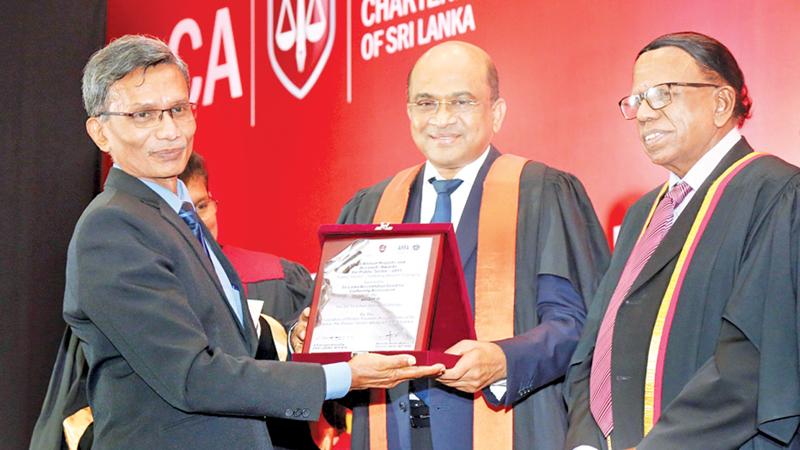  A representative from the public sector organisation receiving the award from Auditor General Gamini Wijesinghe. President of APFASL, V. Kanagasabapathy looks on.   