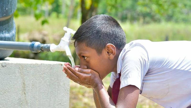 A student of  Medhananda Kanishta Vidyalaya drinks water, after the commissioning of  the treatment plant.   