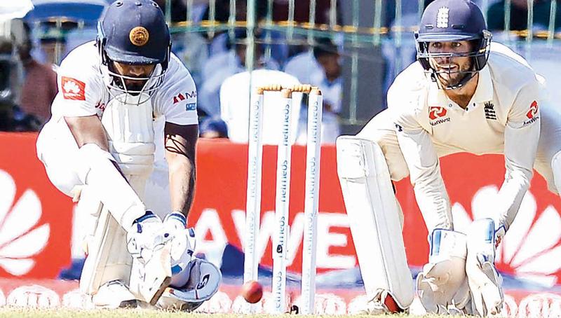 Dimuth Karunaratne reverse-sweeps a ball watched by England wicket-keeper Ben Foakes on the second day of the third and final cricket Test at the SSC ground yesterday (Picture by Saman Mendis)   