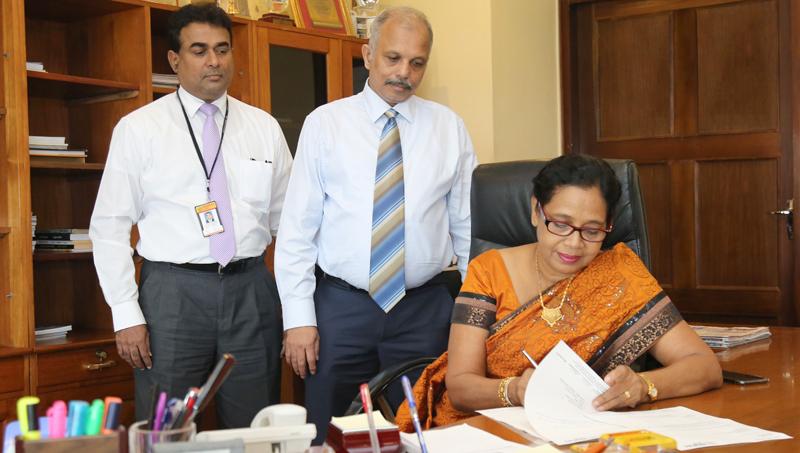 Chairperson of People’s Bank, Mrs Sujatha Cooray assumes duties. CEO/GM N. Vasantha Kumar  and Senior Deputy General Manager/Secretary to the Board of Directors, Rohan Pathirage look on.   