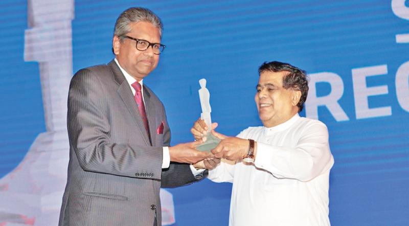 Dr. Harsha Cabral receives the award for 2018 from former Minister Nimal Siripala de Silva.     