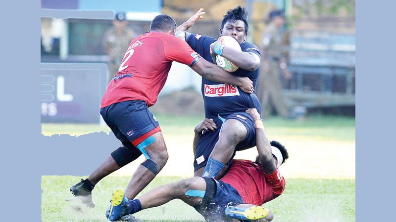 Police hooker Rasith Silva attempts to break through a tackle unleashed on him by two CR defenders in their Dialog League rugby match at Longden Place yesterday Picture by Thilak Perera