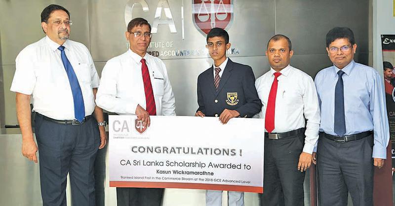 Kasun Wickramarathna of Maliyadeva College, Kurunegala, the first in the island in the commerce stream at the 2018 GCE Advanced Level examination, receives the scholarship from the Institute’s President, Jagath Perera. Vice President Manil Jayesinghe, Council Member Sanjaya Bandara and Secretary Prasanna Liyanage look on.   