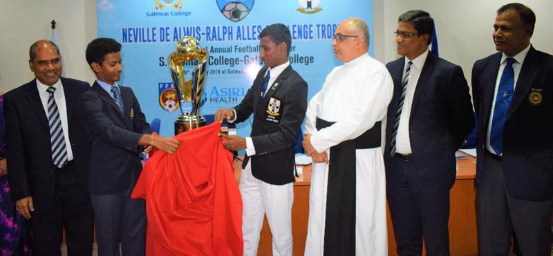 Gateway College captain Rashane Wijewardene (left) and S. Thomas’ College captain DS Ebenezer unveil the Neville de Alwis-Ralph Alles Trophy they will play for in a soccer match as Dr. Harsha Alles (left)Chairman of Gateway and Rev. Marc Billimoria the Warden of S. Thomas’ College look on    (PICTURE BY HERBERT PERERA )    