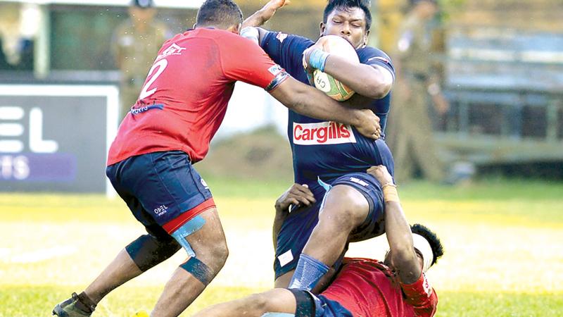 In this file photo Police player Rasith Silva is held by two defenders of CR and FC during their rugby match at Longden Place in Colombo. Police will field a foreign player in their remaining three League matches starting with the first match against Havelocks today at Havelock Park (Picture by Thilak Perera)