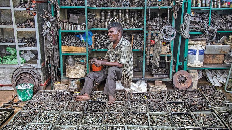 Experienced vendor, P. Kandiah sits on a heap of nuts and bolts laid out in front of him on the pavement of Sangaraja Mawatha