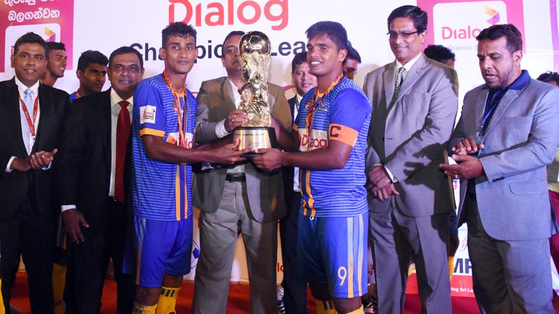 The victorious Defenders SC skipper Roshan Appuhamy (right) and the Most Valuable Player Asikoor Rahuman receiving the Dialog Champions Trophy from chief guest Manusha Nanayakkara