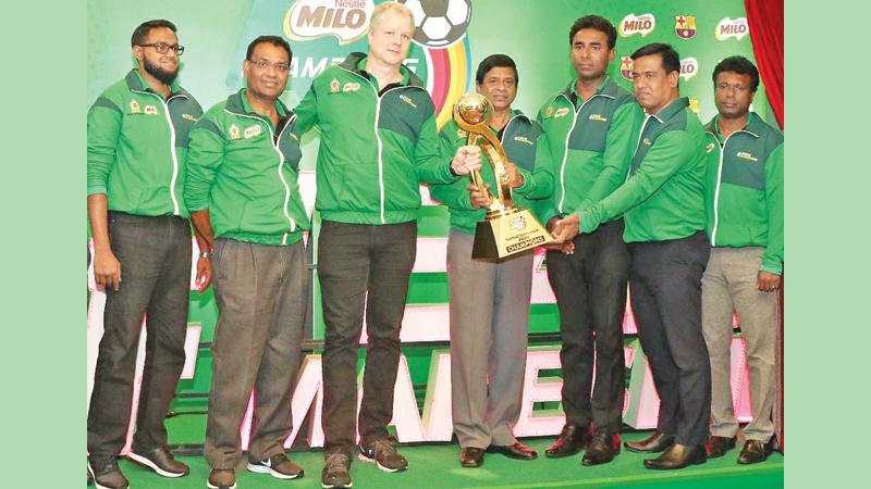 Fabrice Cavallin, (centre) Nestlé Lanka Managing Director, handing over the Milo Football Champions Trophy to Sunil Jayaweera (right), Special Consultant Sports from the Ministry of Education at the launch in the presence of Bandula Egodage, Vice-President Corporate Affairs & Communications at Nestle