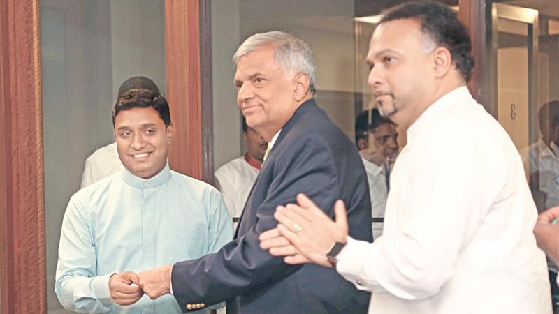 Prime Minister Ranil Wickremesinghe presents the UNP membership card to Talawakele-Lindula Urban Council Chairman Ashoka Sepala who obtained the UNP membership. UNP National Organiser and Plantation Industries Minister Navin Dissanayake looks on. 