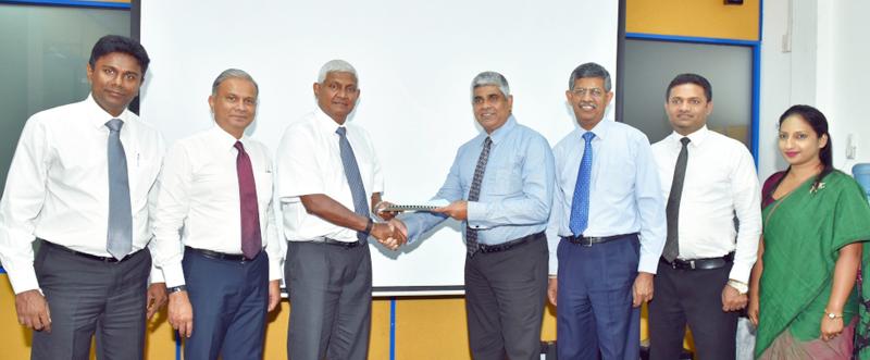 CHSL Chairman R. Renganathan (third from left and National Insurance Trust Fund (NITF) CEO Sanath de Silva exchange the agreement. Senior representatives of the two institutions look on.