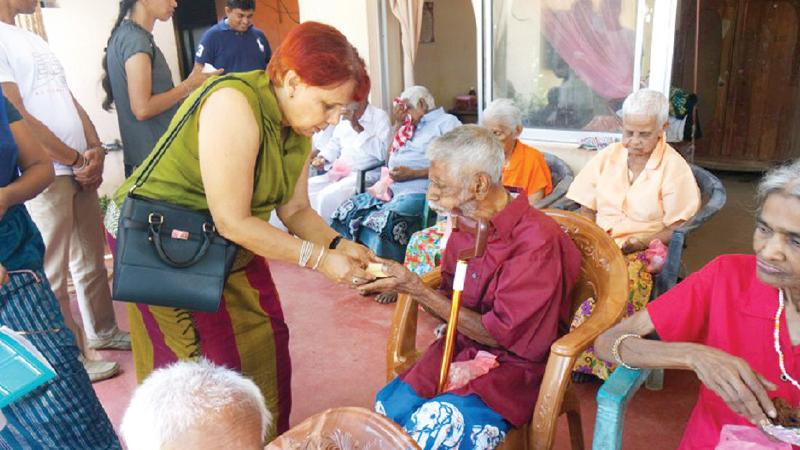 Swarna Wickremasinghe presenting a gift to the Eldest inmate of the Home, 92-year-old D.M. Gunasekera.  