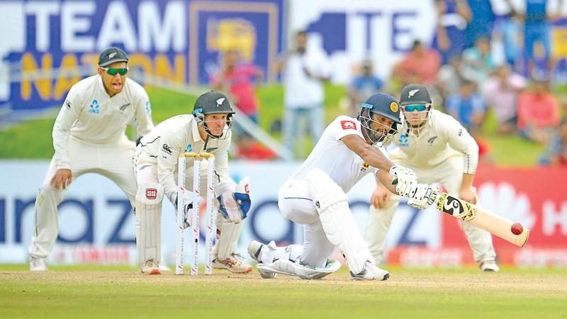 Dimuth Karunaratne sweeps a ball during his unbeaten innings of 71 on the fourth day of the first cricket Test against New Zealand in Galle  