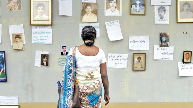 A desperate search: As commemorative events marking International Day of the Disappeared were underway at the OMP office in Colombo on Friday, a mother is seen perusing the memorial wall in search of her missing son’s portrait.  (Pic: Sulochana Gamage)