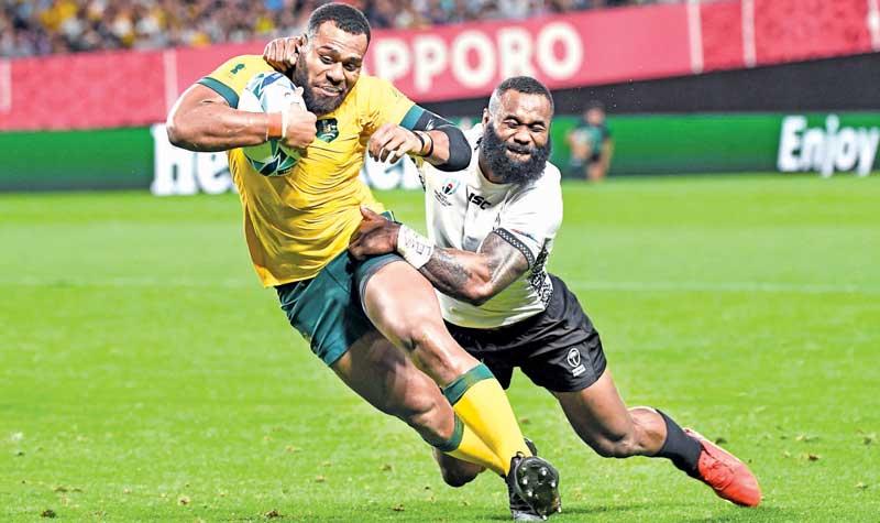 Australia’s centre Samu Kerevi goes through to score a try as Fiji’s wing Semi Radradra tries to tackle him