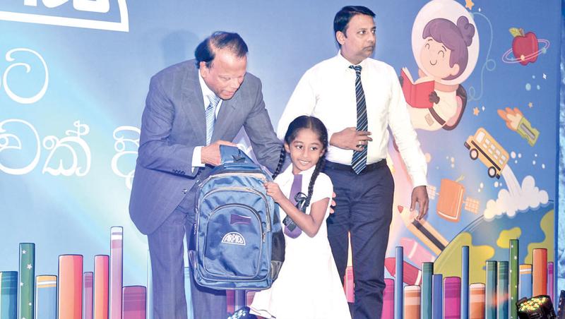 Group Chairman, Richard Pieris and Company, Dr. Sena Yaddehige presents a bag containing school books to a student. Manager, Group Human Resource Operations and Industrial Relations, Richard Pieris and Company, Sydney Gunawardana looks on.