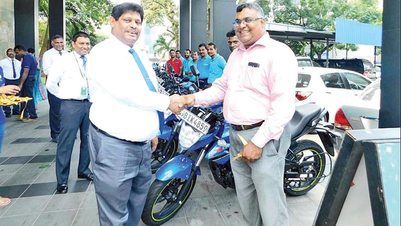 SLIC Chairman Jagath Wellawatta presents a motorcycle to a Motor Technical Officer.  
